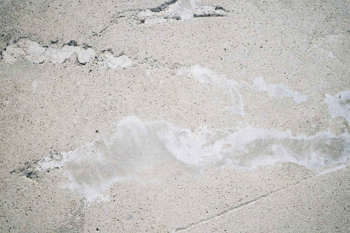 Distressed concrete surface showing cracks and localized delamination
